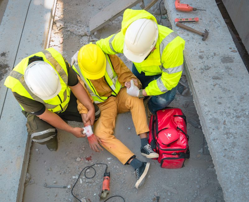 Construction worker has an accident at a construction site. Emergency help engineers provide first aid to construction workers in accidents. Safety team help a construction worker who has an accident.